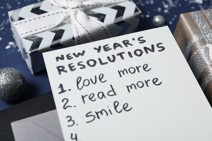 Gift boxes and paper with list on blue background, close up