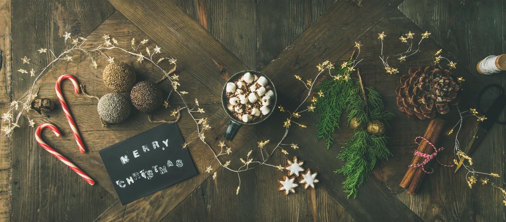 Homely holiday with “Merry Christmas” card, candy canes, pine cones, garland and hot chocolate