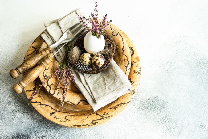 Easter spring card concept with eggs in small nest on rustic plate
