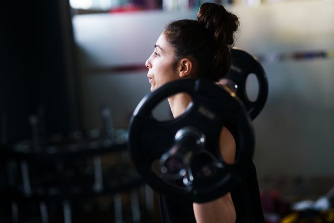 Sporty woman with barbell over her shoulders