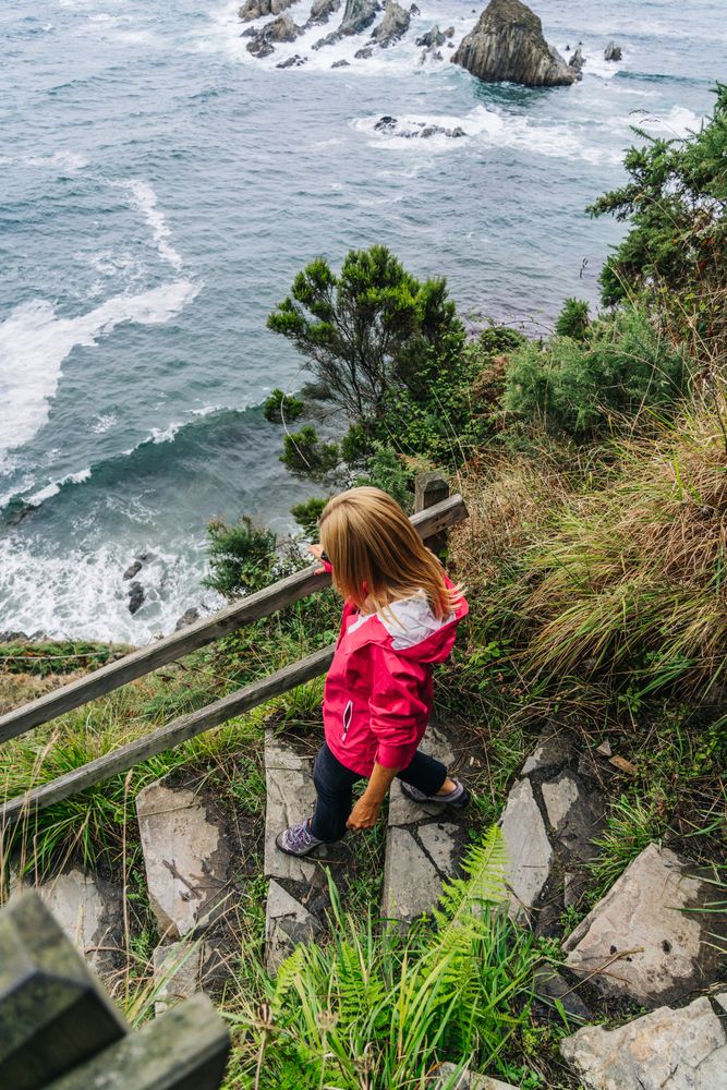 Woman walking down on stone steps leading down to foamy sea