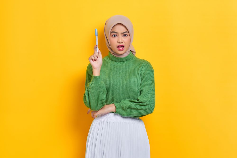 Confused woman in headscarf holding up pen