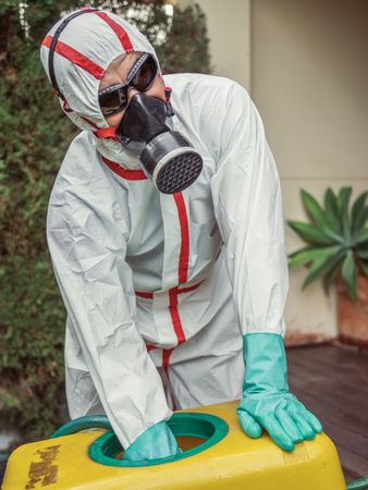 Specialist in uniform for fumigation holding yellow trolley in yard