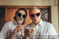 Two men wearing funny sunglasses drinking juice with straw 5zZZj5