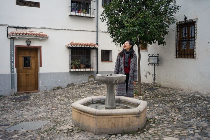 Satisfied female traveler in casual clothing walking amid ancient buildings