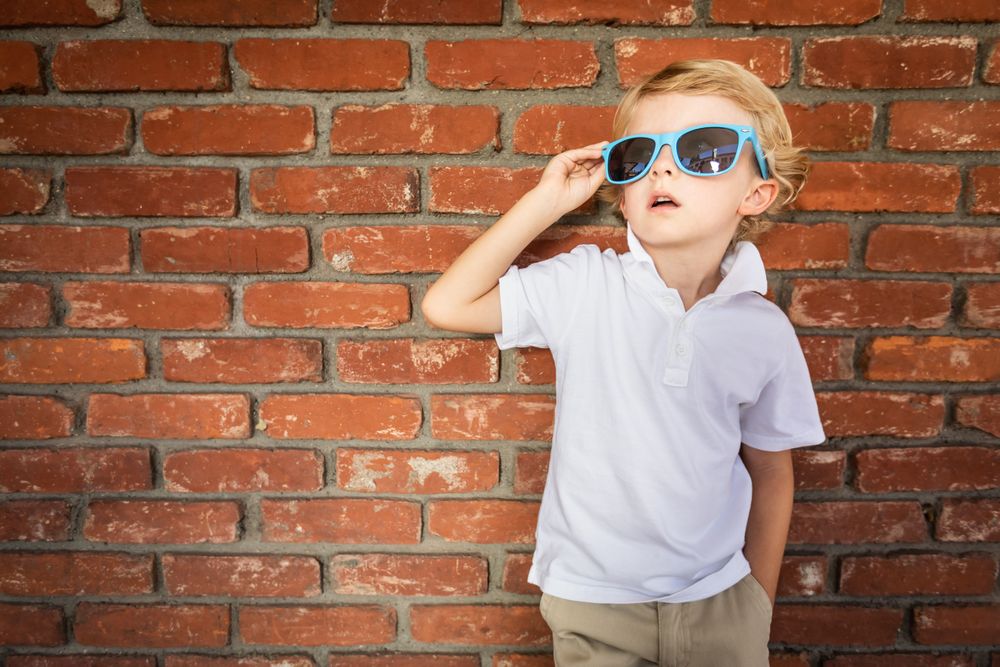 Cute Young Boy Wearing Sunglasses Against Brick Wall