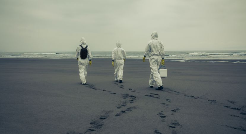 People with bacteriological protection suits walking on the beach