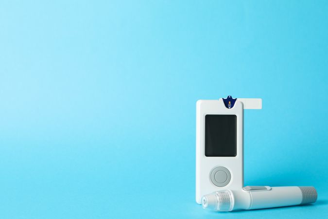 Blood glucose meter on blue background, space for text