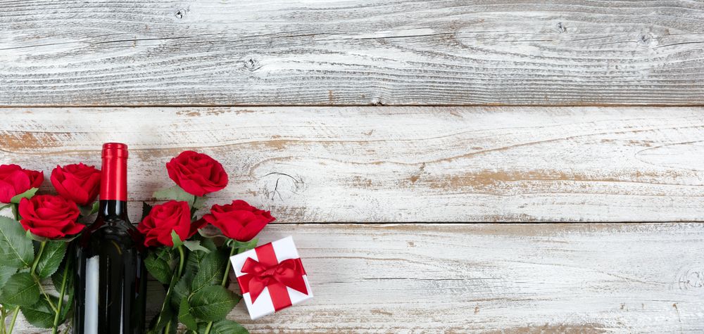 Valentine’s Day celebration with red wine and gifts in lower left hand corner on faded rustic
