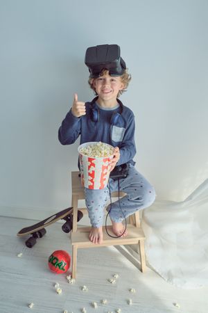 Boy with VR goggles and popcorn showing thumb up sign