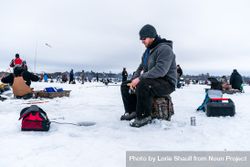 Nisswa, MN, USA - January 25th, 2020: Man sitting with fishing rod ice fishing on a frozen lake bGPlA0