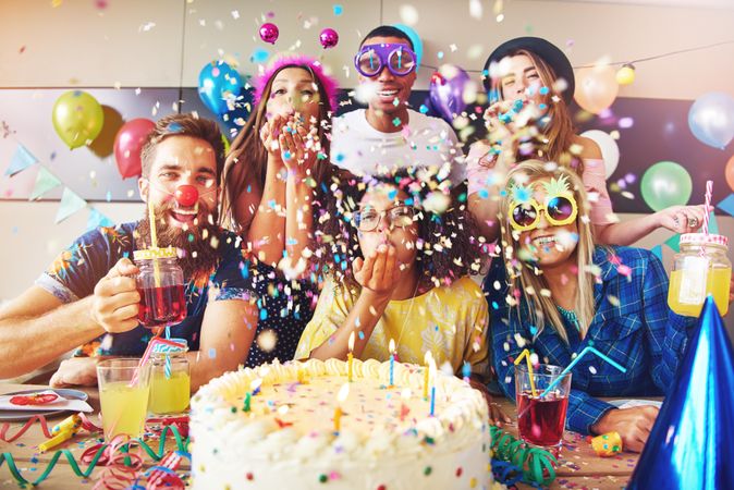 Friends with confetti, cake balloons, drink and cake at birthday party