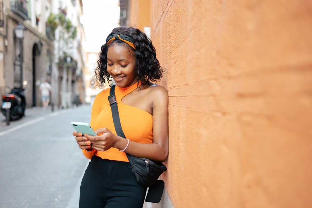 Portrait of a young Black woman using smartphone in the street