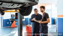 Mechanics making list of repairs on a car in auto service station 56V3e5