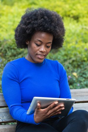 Black woman browsing tablet in city