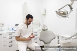 Bearded dentist man holding a jaw model while waiting for patient 5kyZAb