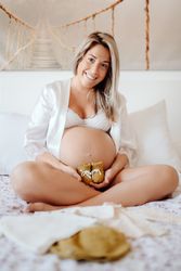 Pregnant woman demonstrating baby clothes