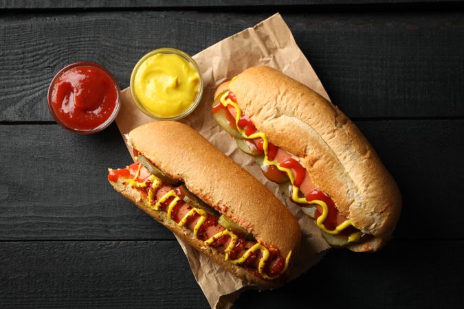 Tasty hot dogs and sauces on wooden background