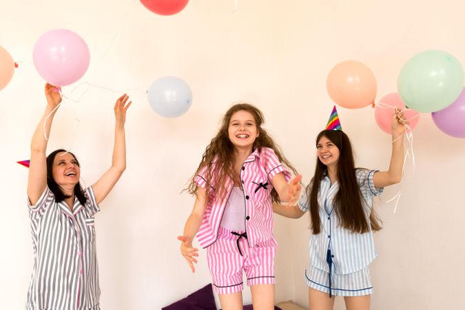Joyful family in party hats playing with balloons indoors.