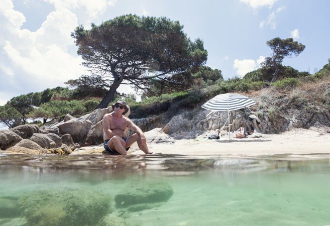 Man lying on sandy shore near water