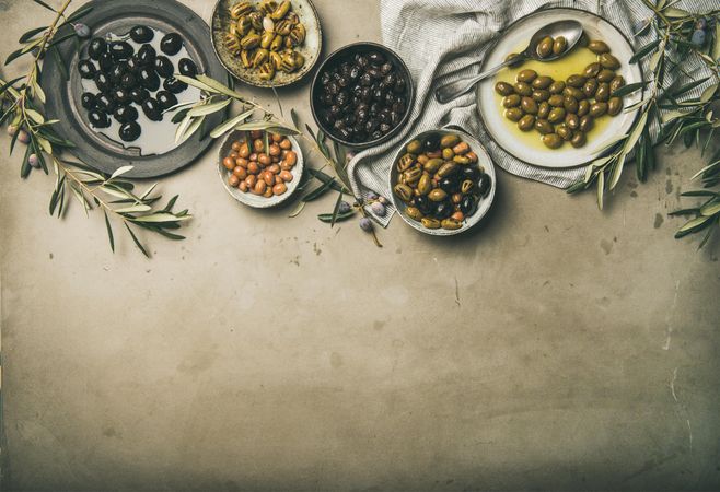 Olives in bowls with branches, on concrete background, copy space, horizontal composition