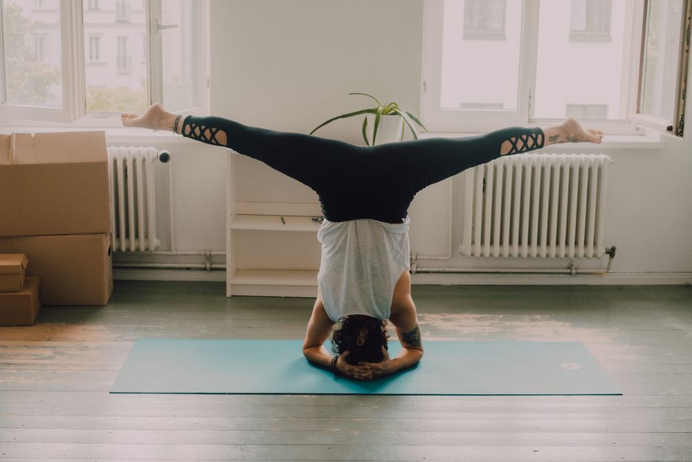 Fit woman practicing yoga pose and standing on head at home