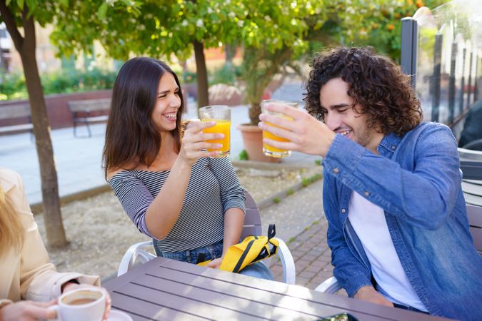 Man and woman smiling with their orange juice outside