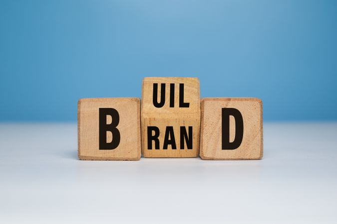 Build brand words symbol with turned wooden block. build your brand concept. isolated on blue background