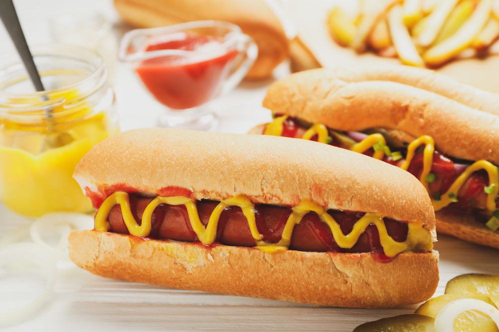 Hot dogs, fries potato and sauces on plain wooden background