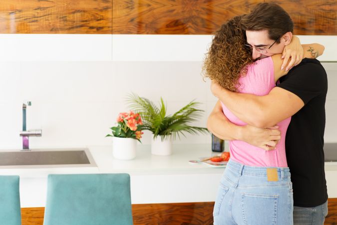 Loving young couple hugging in kitchen at home