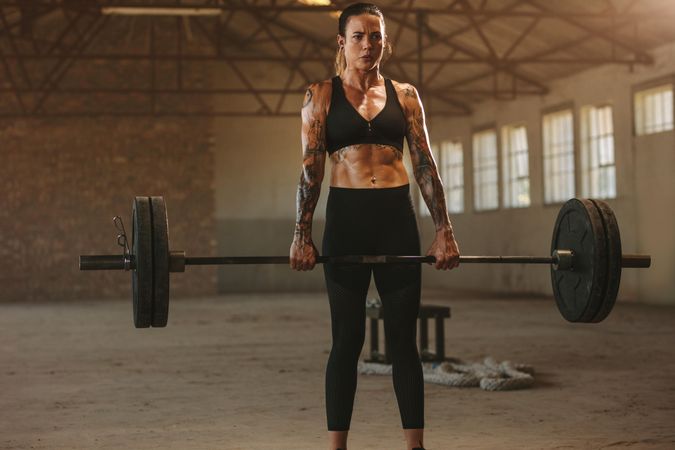 Woman exercising with heavy weights in old warehouse