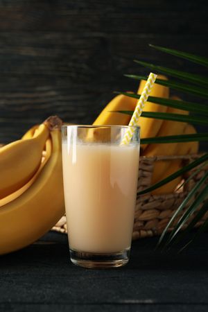 Bananas, juice and palm branch on wooden background. Fresh fruit