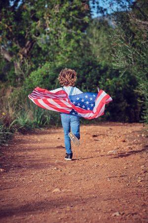Unrecognizable boy running with American flag