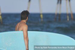 Male surfer with blue board enjoying the view of the ocean 48zR70
