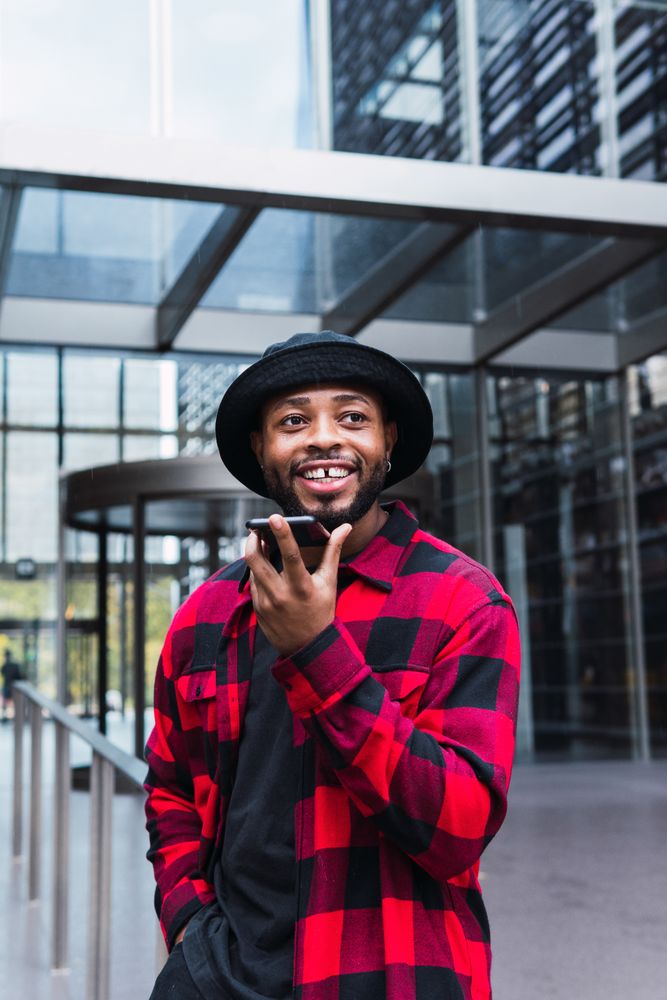 Cheerful Black man talking on smartphone on street