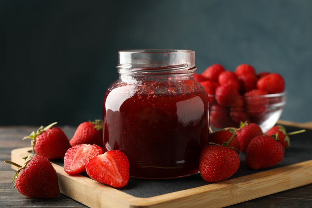 Composition with strawberry jam on wooden table, close up