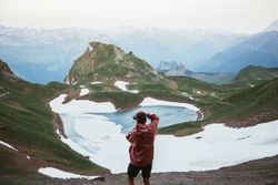 Unrecognizable man taking photo of mountain landscape
