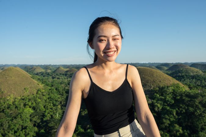 Happy woman standing on observation deck on hill