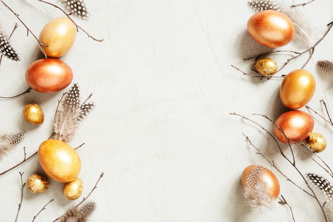 Golden eggs, twigs and bird feathers with copy space