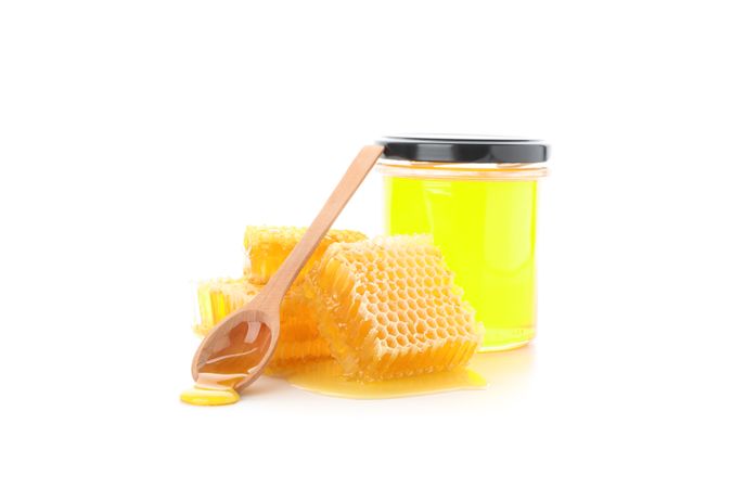 Pieces of honeycomb, glass jar and spoon isolated on plain background