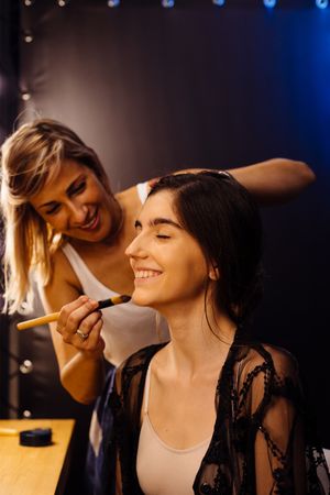 Makeup artist doing makeup for young female artist