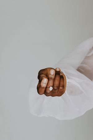 Woman's hand wearing a ring against light background