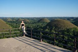 Happy woman standing on observation deck on hill