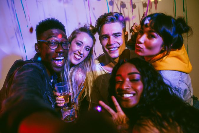 Young men and women posing for a photo and having fun at a colorful house party