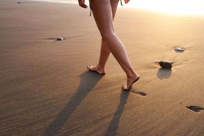 Crop woman strolling on sand of beach