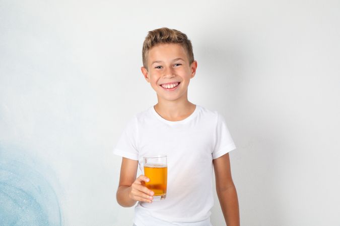 Smile boy with sweet cocktail against light background