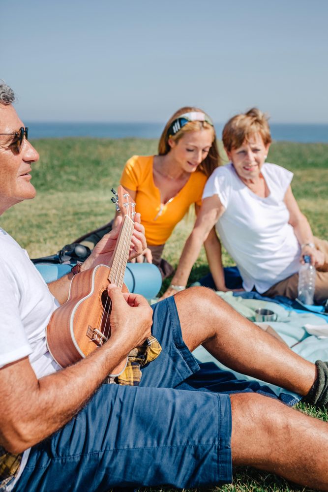 Family on outdoor picnic with ukulele, vertical
