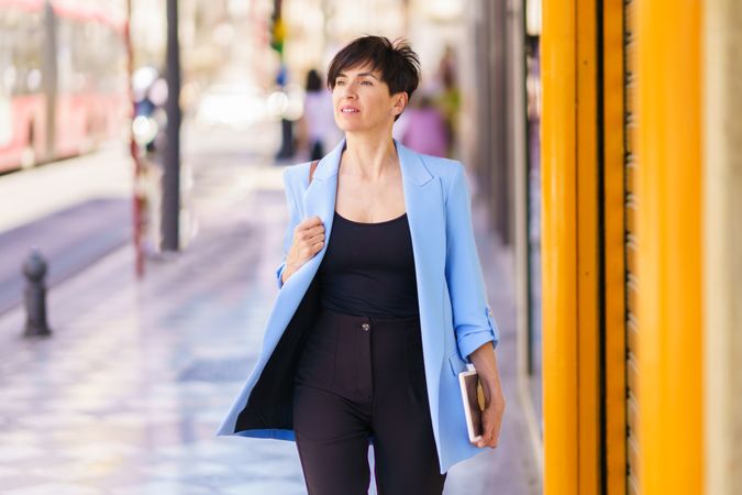 Confident woman in blue blazer walking down street 