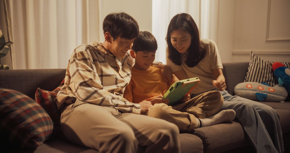 Portrait of Happy Korean Family Using Digital Tablet Computer While Sitting in the Living Room.