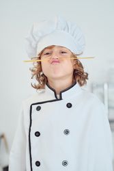 Amusing boy in chef uniform imitating mustache with spaghetti st